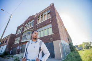 Young man in front of a boarded-up building