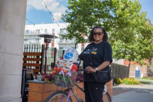 woman with a bike stands in front of a housing complex