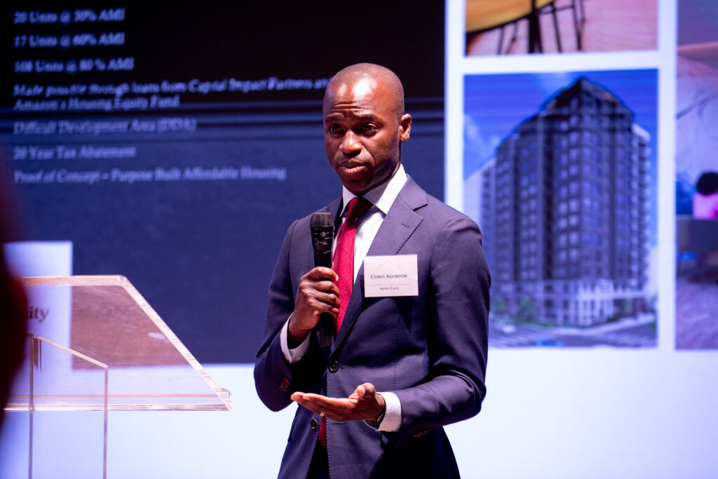 Black man in a suit holding a microphone and conducting a presentation