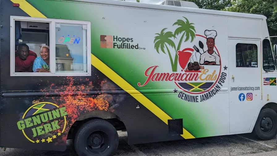 A couple, including  Cynthia Pinchback-Hines, owner Jamerican Eats’, smile from the window of a food truck